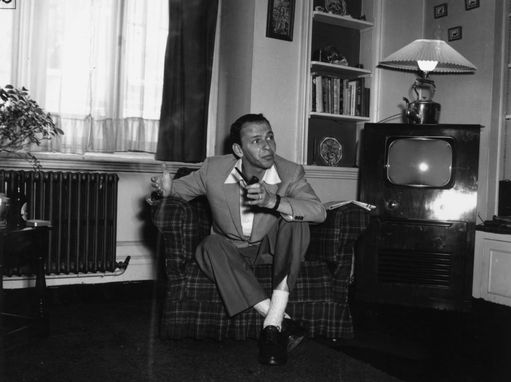 29th June 1953: Popular American singer Frank Sinatra relaxing with a pipe at his flat in Mayfair, London, before his concert at the Palladium. (Photo by R. Mitchell/Express/Getty Images)