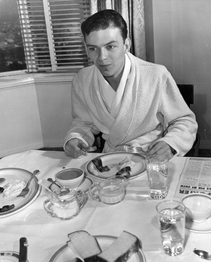 circa 1940: A young Frank Sinatra in his dressing gown tucks into some bacon and eggs. (Photo by Hulton Archive/Getty Images)