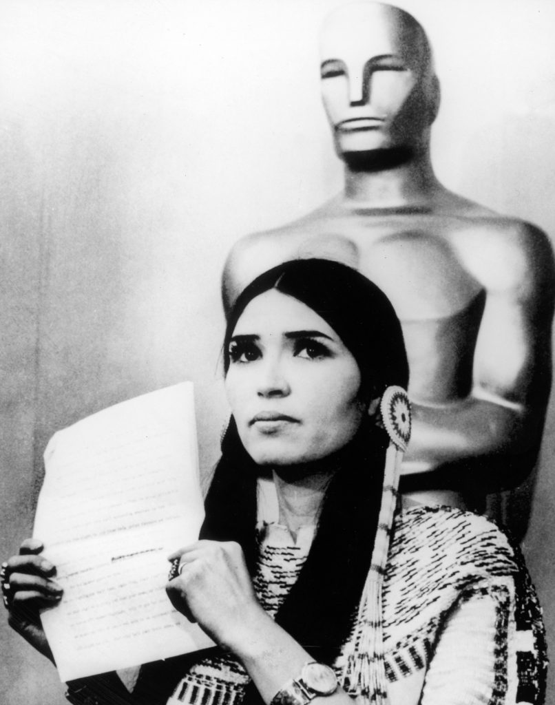 27th March 1973: Sacheen Littlefeather (Native American actress Maria Cruz) holds a written statement from actor Marlon Brando refusing his Best Actor Oscar on stage at the Academy Awards, Los Angeles, California. (Photo by Hulton Archive/Getty Images)