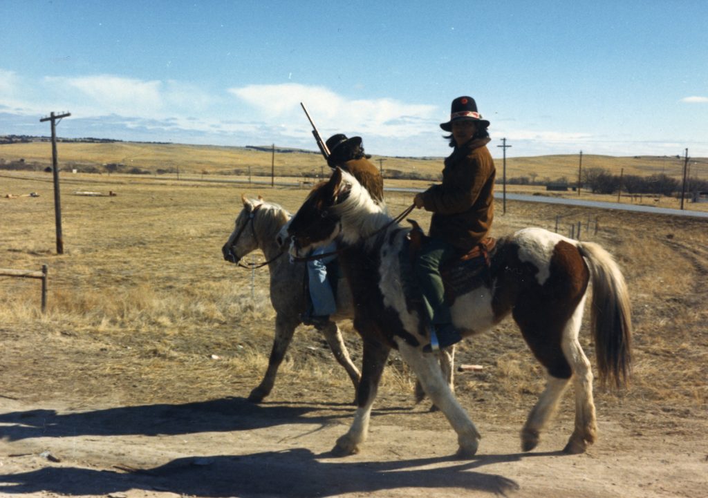 Two armed members of the American Indian Movement (AIM) on horseback patrol along a street during their occupation of the town of Wounded Knee on the Pine Ridge Reservation, South Dakota, 1973. AIM occupied the town, exchanging gunfire with local and federal troops, from February 27 through May 8, 1973, following internal reservation disputes as well as disatisfaction with the US government's treatment of Native American peoples in general. (Photo by Peter Davis/Getty Images)